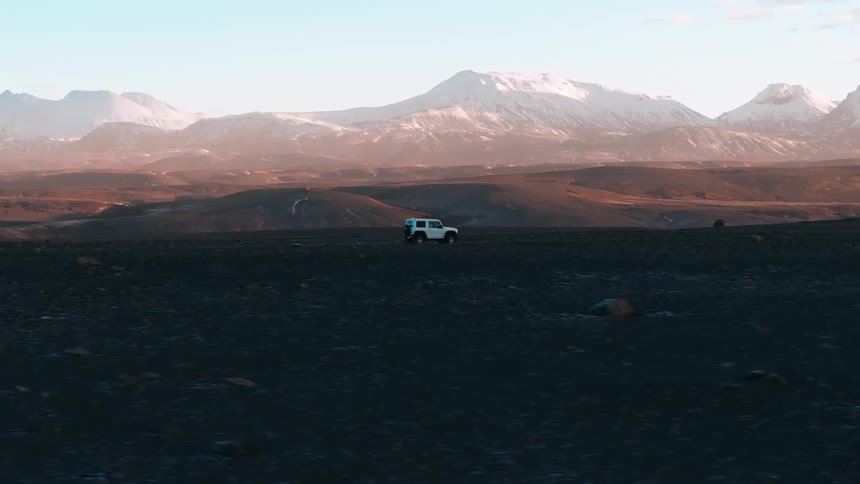 A car drives across a plain in a mountain valley