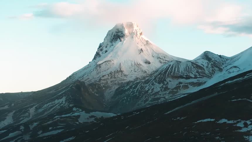 Landscape of a mountain peak covered by snow in a morning sky