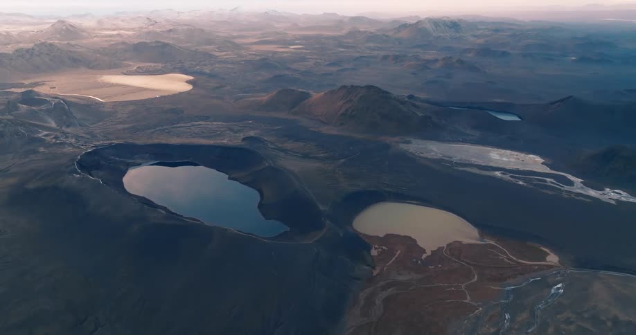 Aerial of small lakes between mountain valleys during cloudy dawn