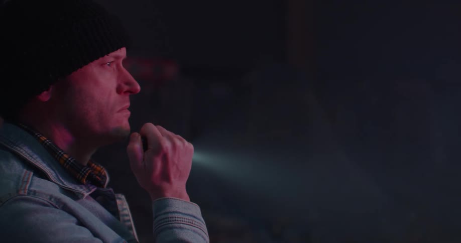 Man holding a flashlight and checking a dark room