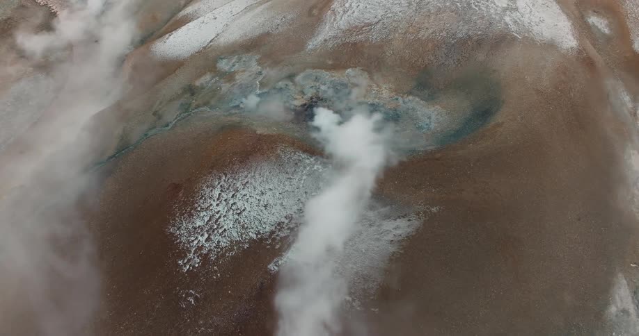 Steam rising from multiple spots on a geothermal terrain