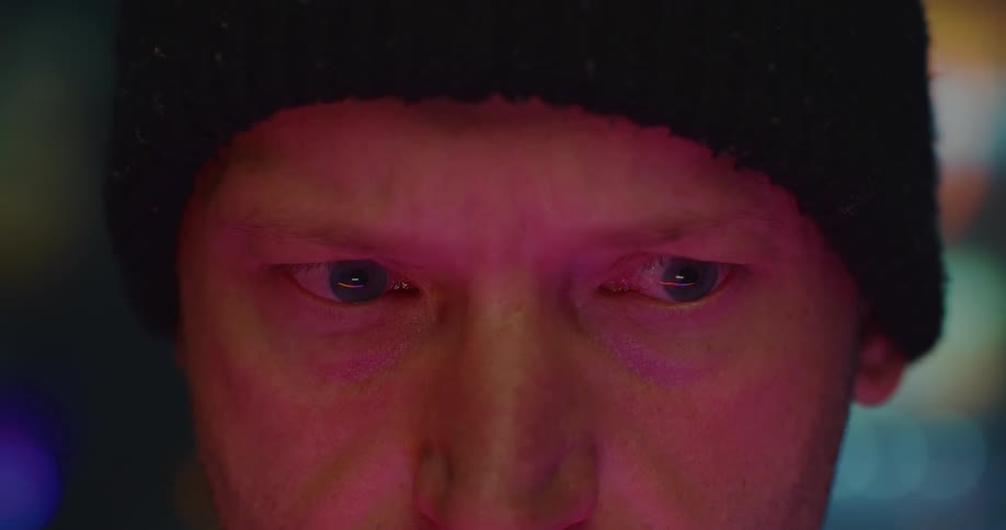 Close up of the eyes of a man looking around under red lights