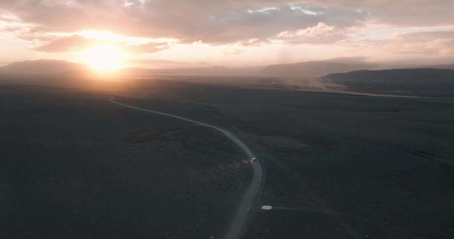 A car drives down a road near mountain ranges