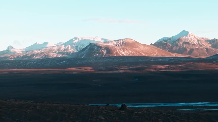 A landscape of mountains with snowcapped peaks under a clear sky