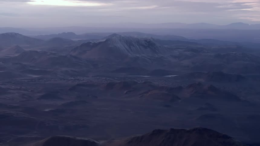 A panoramic view of a mountainous terrain with rugged surfaces at evening