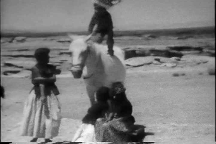 A native american boy stands on a horse