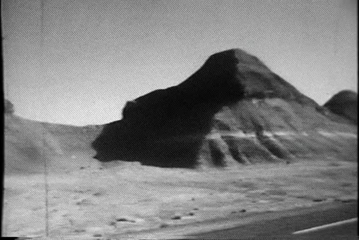 Panning view of desolate hills with a road going through them