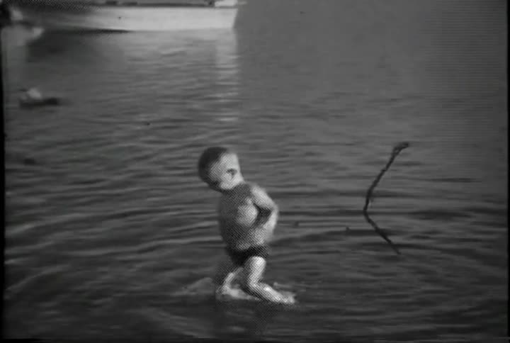 A young boy is playing in the water at a lake