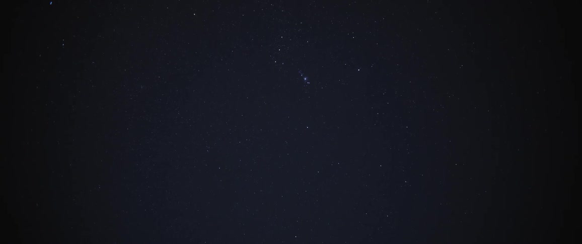 Two stars shoot across the night sky in opposite directions