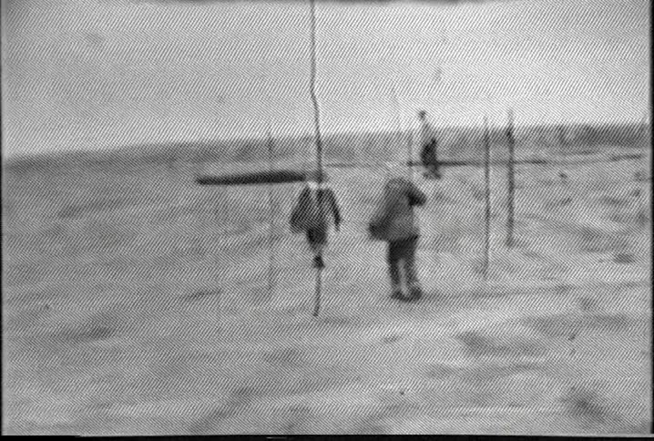 A group of adults and children walking on a dune on a breezy day