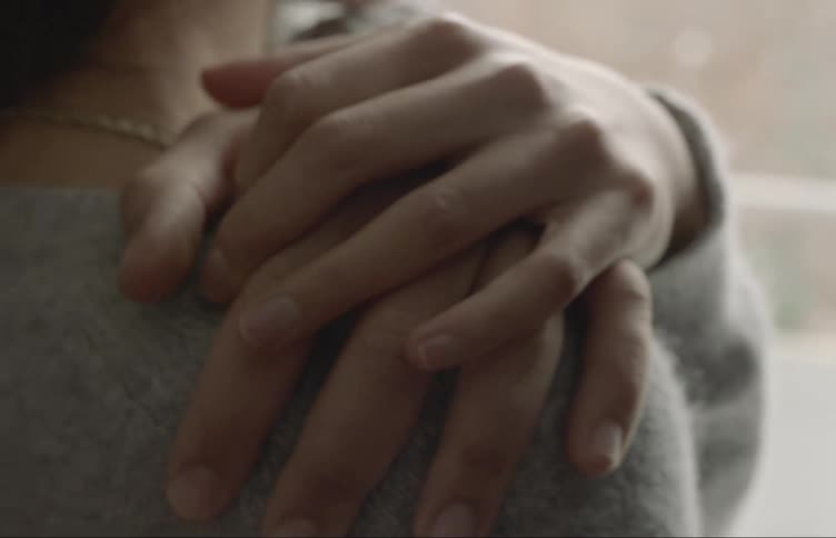 A man grabs a womans shoulder and she covers her hand with his
