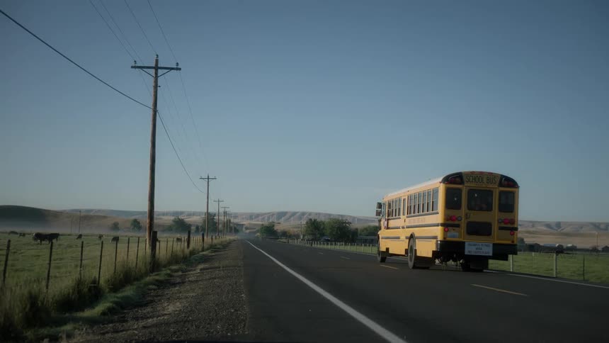 A school bus drives down a remote road