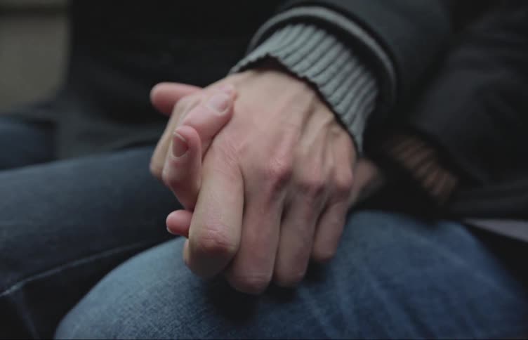 Two people holding hands sitting close to each other