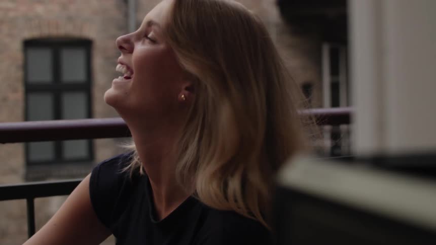A blonde woman is smiling at something next to her