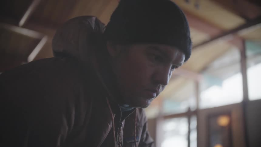 A man wearing a beanie concentrates on his task at hand
