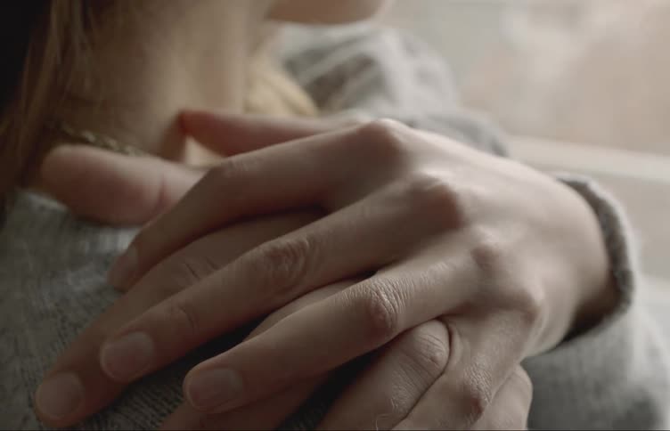 A woman clasps hands with another persons hand on her shoulder