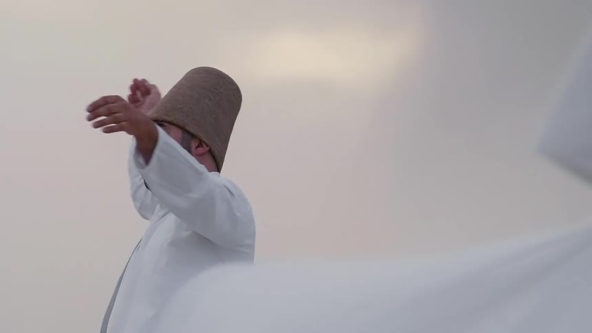 Sufi dervish wearing hat and formal white clothing with hands raised to the sky spinning