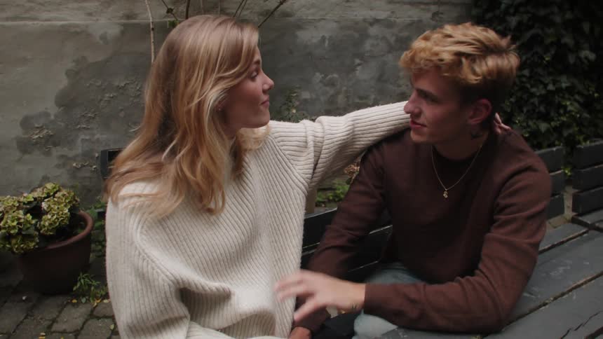 A couple talking on a wooden bench in the backyard