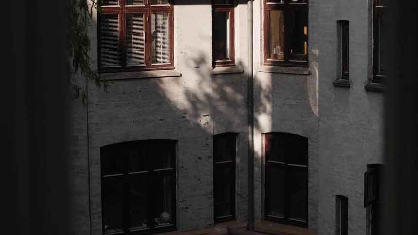 A building with white walls and open windows illuminated by the sun