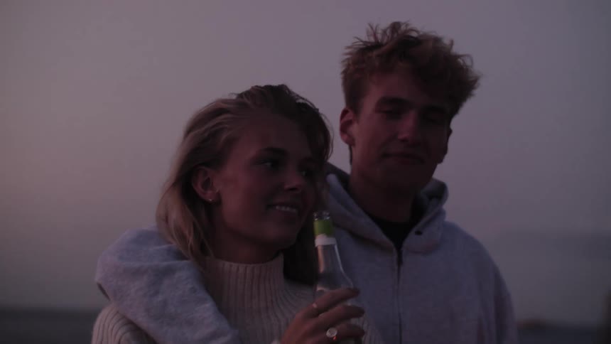 A young man has his arm around his female companion while outdoors
