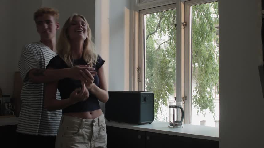 A woman and a man hugging in the kitchen at home