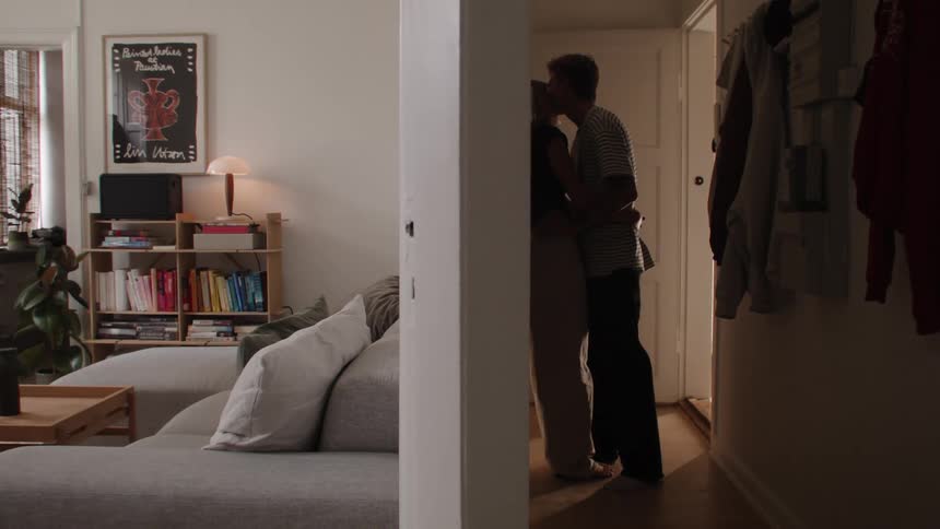 A couple hug and kiss near a doorway