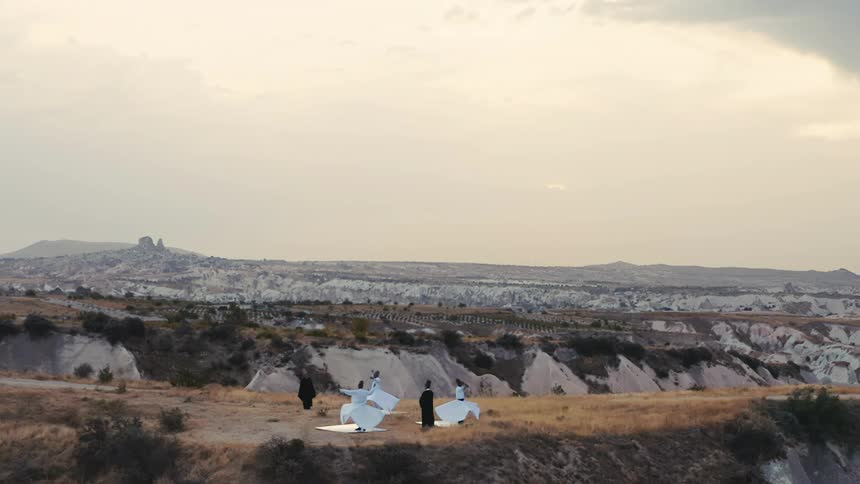 Three women dance on a plateau as two men look on