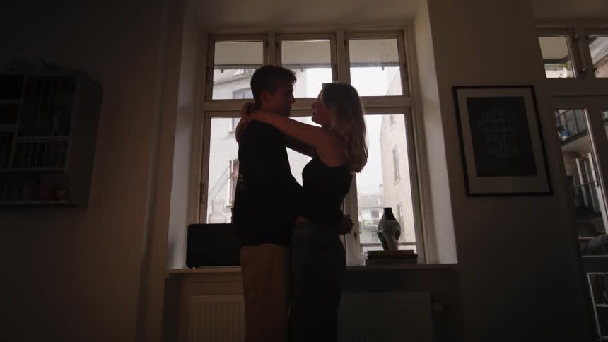 Couple in a room hugging each other while standing and giving each other a kiss in a romantic way