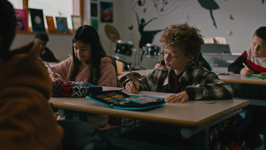 Students in the classroom concentrated with a boy and a girl talking to each other while writing