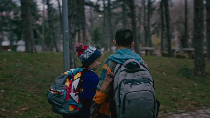 Two friends meet in the woods and greet each other and start walking together
