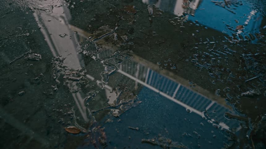 Closeup of the ground with still water reflecting a handril during the day