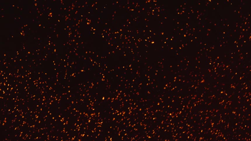 Glowing embers move as they float in the darkness