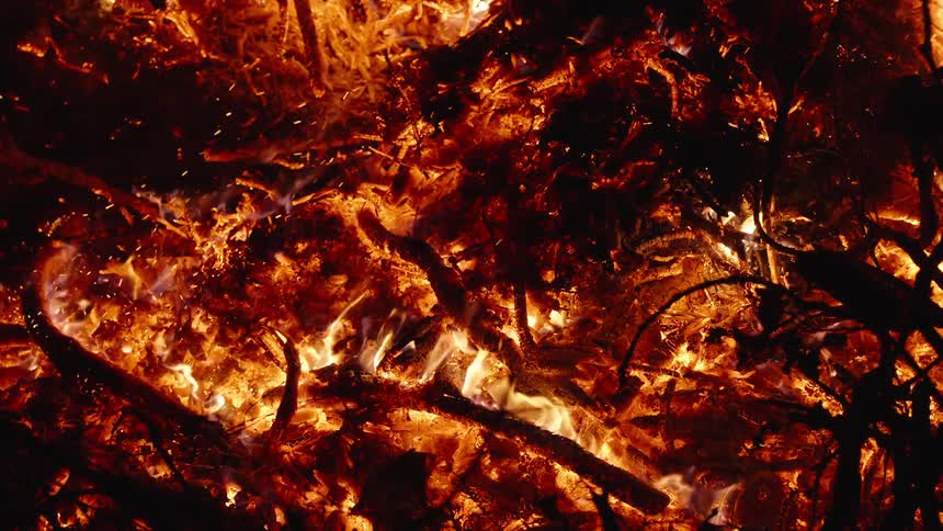 Bright flames and embers consume wood at night
