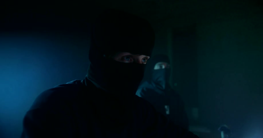 Two people are dressed in all black with masks