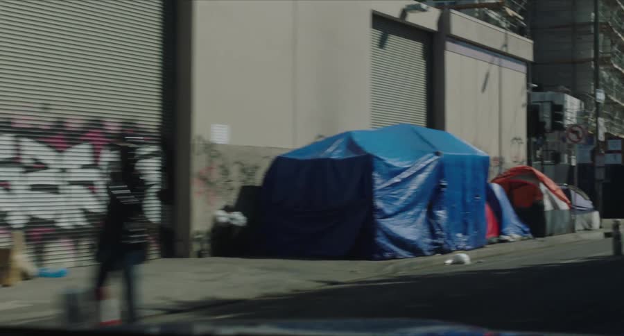 Tents on the sidewalk of a city street during the day
