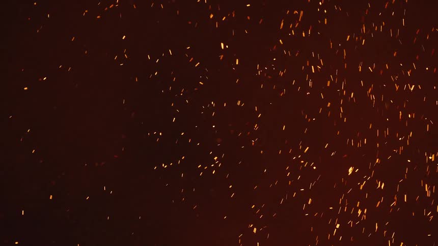 Ember of fire rising into the air with smoke at night