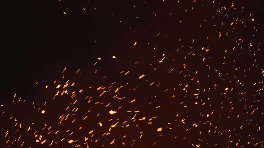 Glowing embers move as they float in the darkness