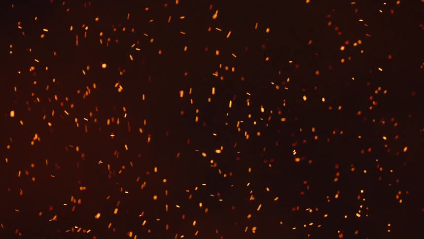 Glowing embers move as they float in the darkness