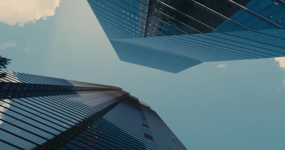 A view of a city street with many tall buildings seen from below