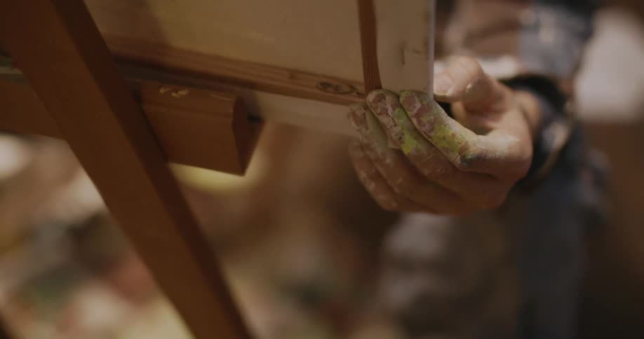 Close up of an artists hand with his hand dirty with paint