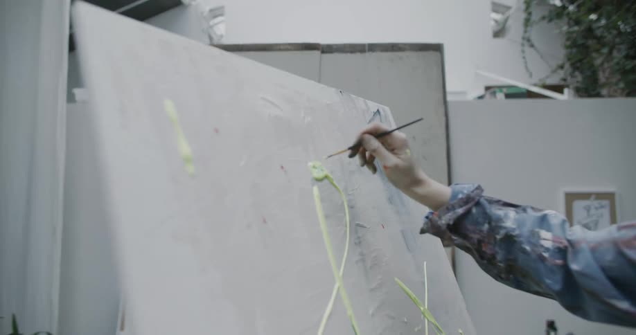 A woman painting a blank canvas with green paint