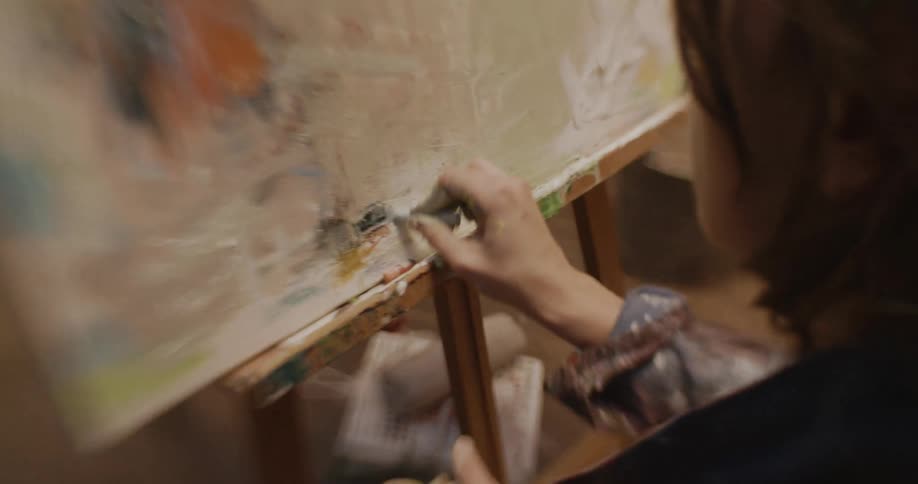 A concentrated person painting an art canvas