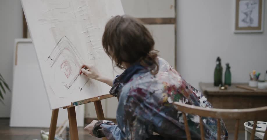 A woman painting a canvas with crayons