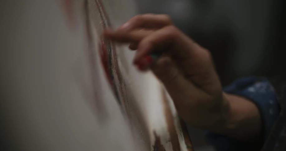 A woman using wax pencils to paint on canvas