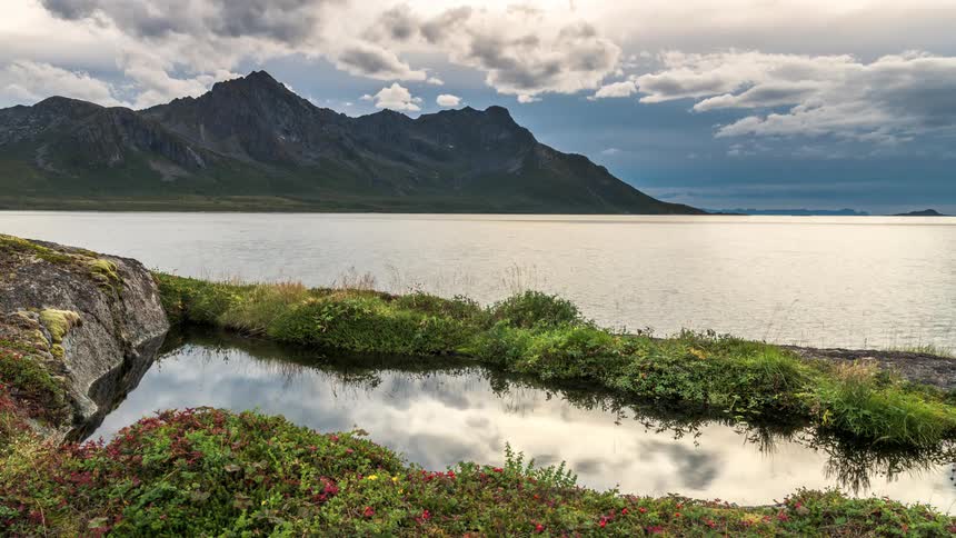Still sea is surrounded by mountain range