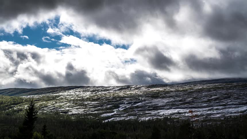 Clouds floating over snowy hill