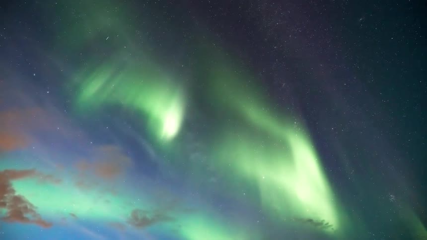 The aurora borealis glows among stars in the night sky