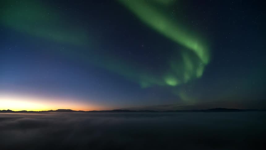 A green beam of an aurora borealis in a clear morning sky
