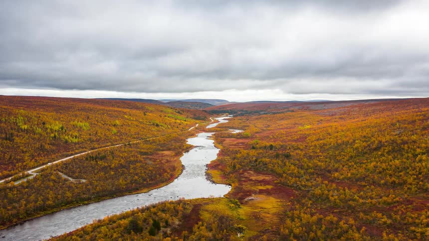 Aerial view of a river and a half abuse and mountains with forests on a cloudy day