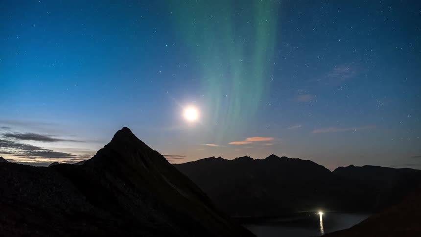 Aurora borealis happening during the starry night illuminating the mountains